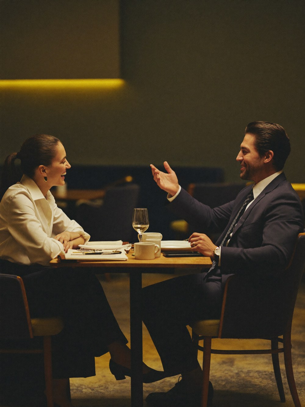 Two professionals in warm conversation across a small table in an upscale lounge